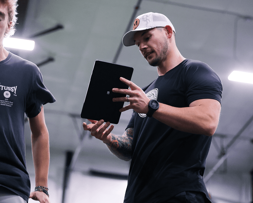 Coach Justin reviewing notes on a tablet with an athlete